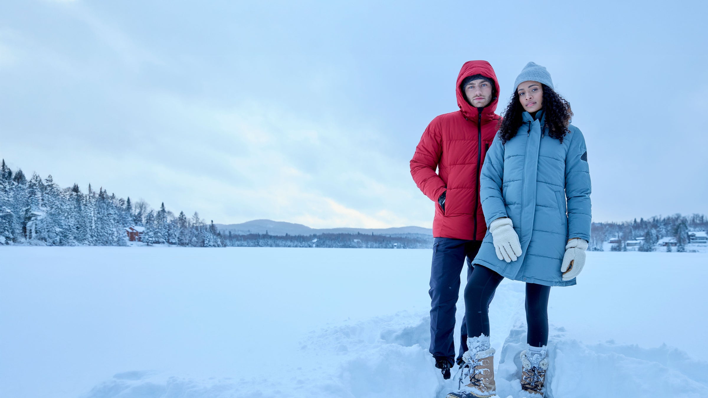 Two people standing on a snow-covered landscape with a clear sky.